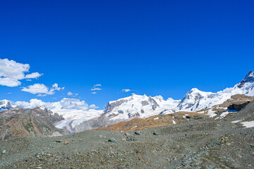 Swiss Alps peaks and ridges covered in snow in Summer. Stunning mountain landscape in Switzerland. Panoramic shot. Space for copy. 