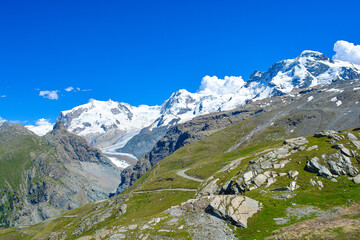 Swiss Alps peaks and ridges covered in snow in Summer. Stunning mountain landscape in Switzerland. Panoramic shot. Space for copy. 