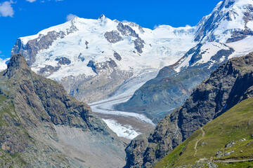 Swiss Alps peaks and ridges covered in snow in Summer. Stunning mountain landscape in Switzerland. Panoramic shot. Space for copy. 