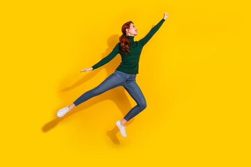 Full length photo of shiny attractive lady dressed green sweater jumping hign rising fist empty space isolated yellow color background