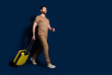 Photo portrait of mature age brunet bearded funny man in beige t shirt going to his plane with baggage isolated on dark blue color background