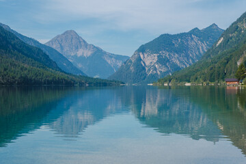 Tranquil reflections of mountains and trees in the serene waters of Plansee, Austria