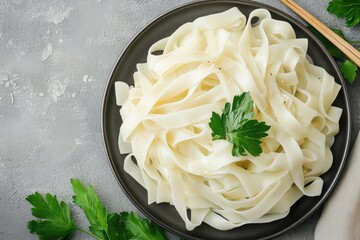 Fresh cooked flat rice noodles on black plate with parsley
