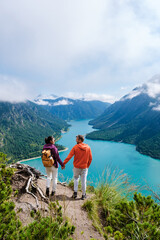 Two hikers enjoy breathtaking views over the turquoise lake in Plansee, Austria on a clear day