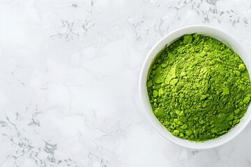 Matcha green tea powder in bowl on white marble background, top view