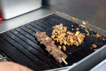 A person is cooking anticuchos on a grill