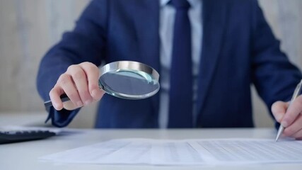 Businessman is carefully examining financial documents with a magnifying glass, highlighting the importance of thorough analysis in business. Audit and taxes