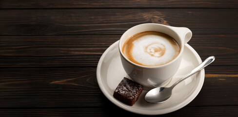 Hot cappuccino on a dark wooden background