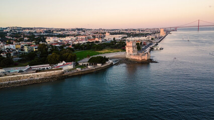 Fototapeta premium An aerial drone image of the iconic Belém Tower in Lisbon, Portugal, set against the serene backdrop of the Tagus River at sunset. Lisbon
