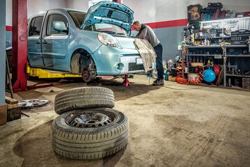 Blue car in car service, auto repair workshop, wheel tire replacement