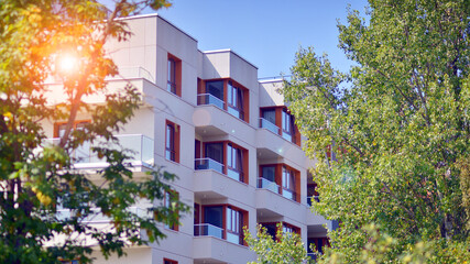 A apartment building with a lot of balconies and windows. The building is surrounded by trees and has a lot of greenery. Green surroundings of buildings. Ecological housing estate.
