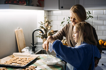 Mother and daughter baking Christmas cookies together, holiday traditions, family bonding, festive kitchen, creating memories, holiday spirit, Christmas preparation.