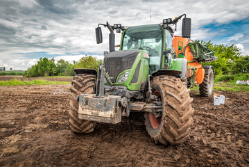 Tractor working on the plowed farm field, agricultural transport, pesticide
