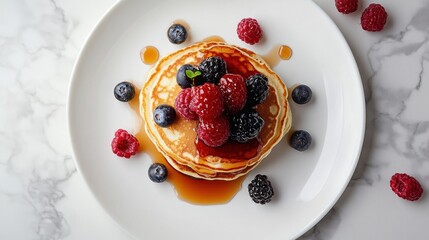 A plate of pancakes with berries and syrup on top