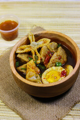 Meatballs, eggs and dumplings served with spicy sauce in a wooden bowl