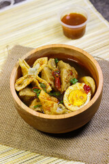 Meatballs, eggs and dumplings served with spicy sauce in a wooden bowl