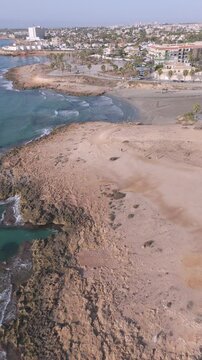 Vertical aerial shot of Playa Flamenca featuring the tranquil beaches and rocky coastline of Orihuela Costa, Spain, perfect for holiday backgrounds.