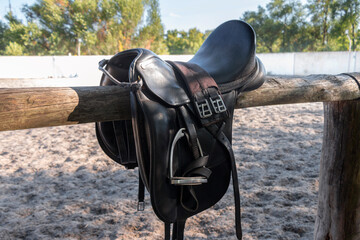 Leather saddle with stirrups for show jumping race. Saddle for riding horse. Horse saddle on rural...