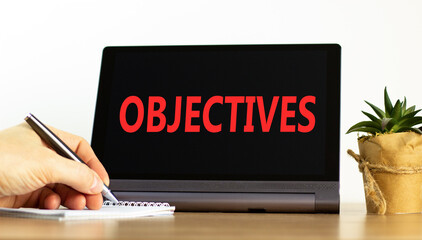 Objectives symbol. Concept word Objectives on beautiful black tablet. Beautiful wooden table white background. Businessman hand with pen. Business objectives concept. Copy space.