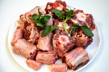 Raw beef oxtail on a round white plate in closeup.