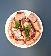 Raw beef oxtail on a round white plate in closeup.