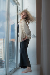 Obraz premium Caucasian woman dancing modern dance on the windowsill. Vertical photo. 