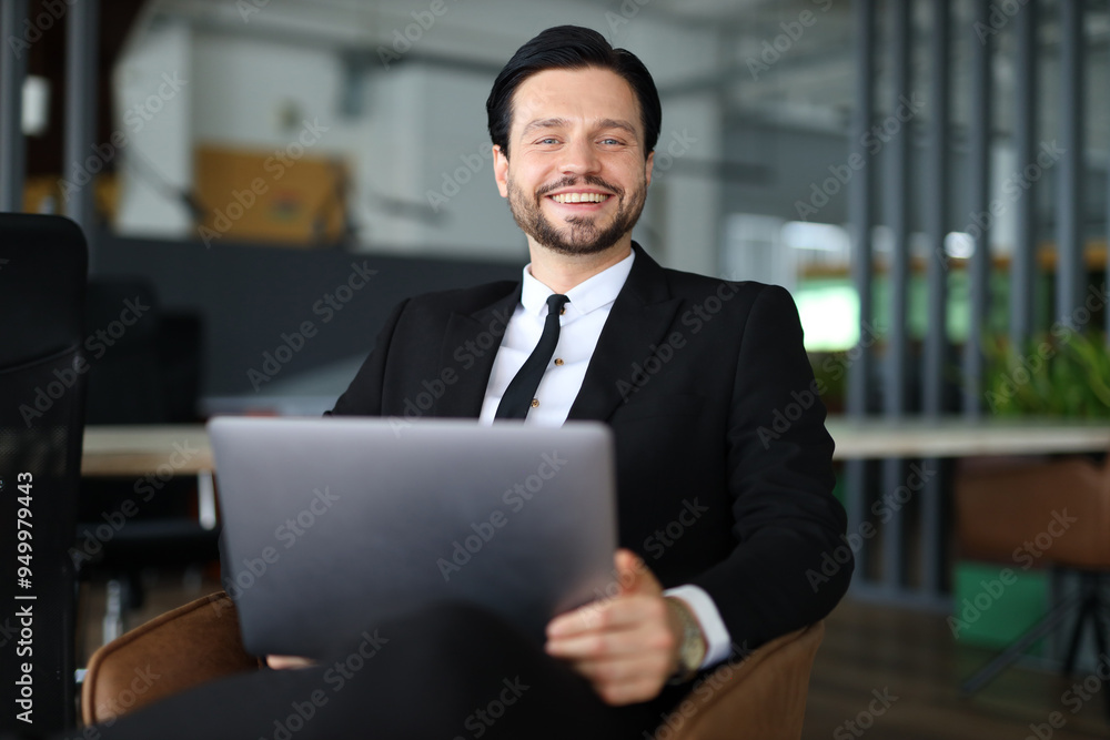 Poster a man in a suit and tie is sitting in a chair with a laptop in front of him. he is smiling and he is