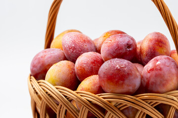 Beautiful ripe sweet plums in a basket isolated on white background. Close up.