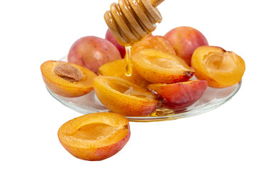 Halves of ripe sweet plums with honey on a glass plate isolated on transparent background.