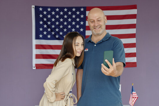 People making selfie portrait on smartphone against American flag during voting
