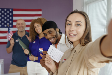 Young woman making selfie portrait with other people at election day