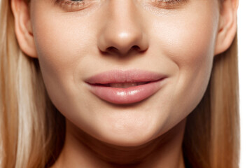 Obraz premium Plump female lips. Lip augmentation. Close-up cropped image of female lower face part with well-kept skin and hydrated lips. Concept of lip care, moisturizing and plumping cosmetic products