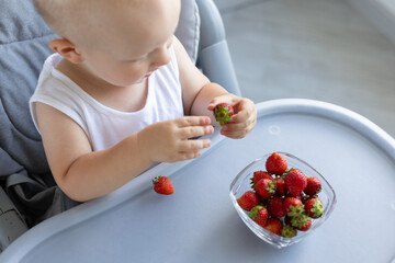 Little child peel strawberry. Child eating berries.