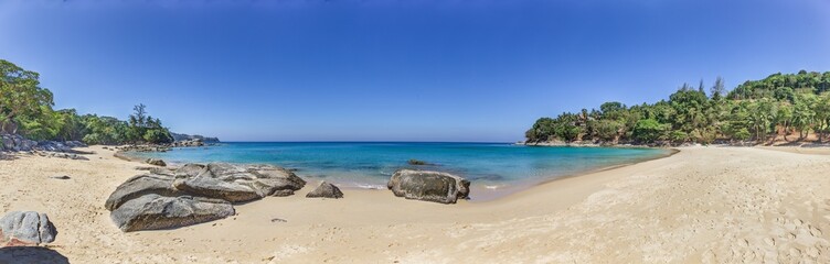 Panoramic picture of a deserted, palm-covered, tropical sandy beach
