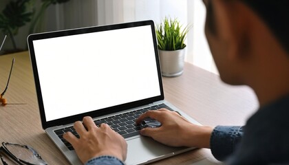 Over shoulder shot of a young man using computer laptop in front of an blank white computer screen in home