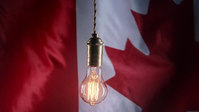 Flashing classic antique Edison Tungsten filament lamp on waving canadian flag background. Creative idea, realization, discovery, eureka