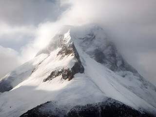 A very tall mountain covered in snow on a cloudy day