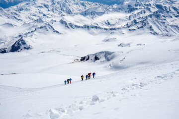 A group of people walking on the snowy mountains with their snowshoes on. Climbing the icy mountains