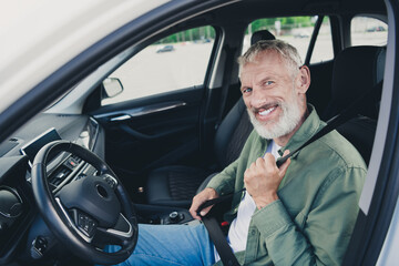 Photo of attractive funny retired guy wear khaki shirt fasten automobile seat belt outdoors urban city street