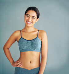 Fototapeta premium Woman, portrait and confident in studio for fitness, smile and runner for body health challenge. Background, workout results and satisfaction for progress, proud and happy with athlete for sport