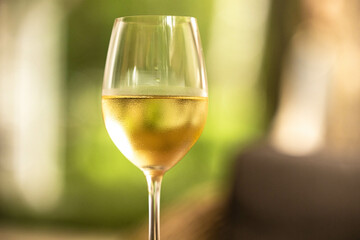 A refreshing glass of white wine sits elegantly, catching the light in a bright and cheerful atmosphere.