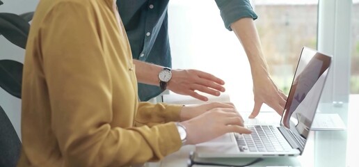 Team collaboration over financial reports. Close-up view of two business people, professionals analyzing financial charts and data on a desk near a laptop computer