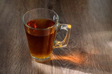 tea in glass cup on wooden table with bright, relaxing tea time concept