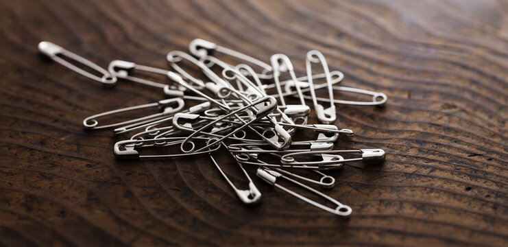 Safety pins on or a pin on a rustic wooden table.