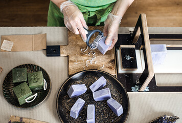 Overhead view of handmade lavender soap bar being shaped with peeler. Soap making, sustainable...