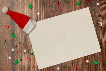Empty white paper with candies on wooden background from above. Flat lay, top view. Space for text.