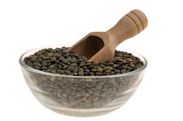 Saladier de lentilles du Puy sèches avec une cuillère à doser en gros plan sur fond blanc