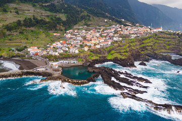 Fototapeta premium Coastal town Seixal on north Madeira island with stormy waves of Atlantic ocean. Aerial view