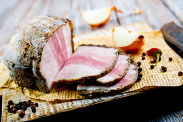 Smoked lard, bacon, half a piece, on a wooden dark craft board. Top view, close-up.