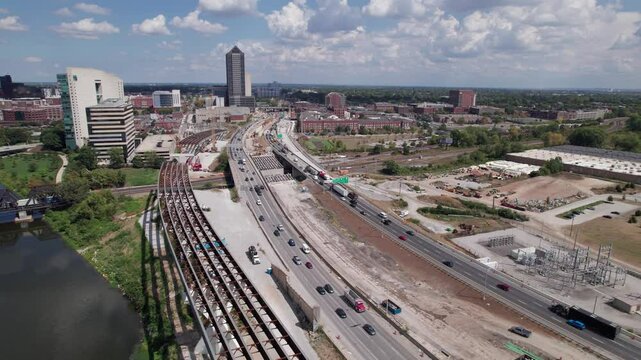 Drone aerial of new highway and multi land interstate construction coming soon and being built next to downtown and city center of Columbus, Ohio with turnpike car traffic and workers near buildings
